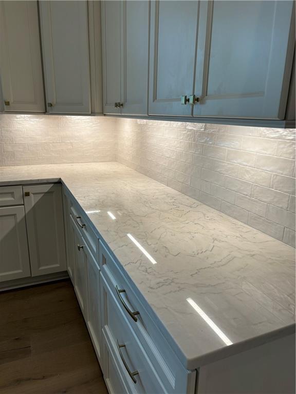 11 Khan Ct, Metairie, LA 70003 - kitchen with dark wood-style floors, light stone countertops, and decorative backsplash