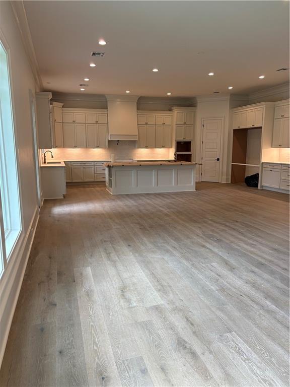 kitchen featuring a sink, ornamental molding, custom range hood, and visible vents