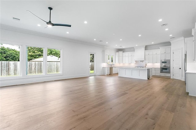 11 Khan Ct, Metairie, LA 70003 - unfurnished living room with plenty of natural light, crown molding, a ceiling fan, recessed lighting, and light wood-style flooring