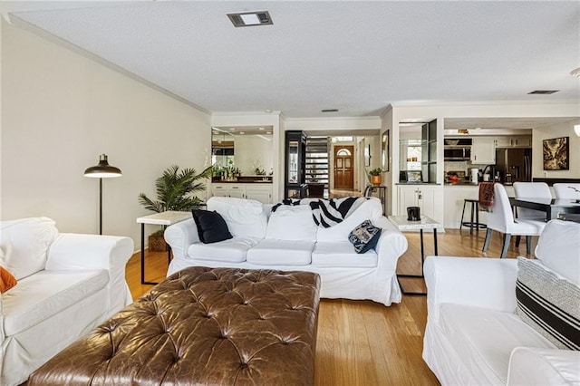 living room with light wood-type flooring and crown molding