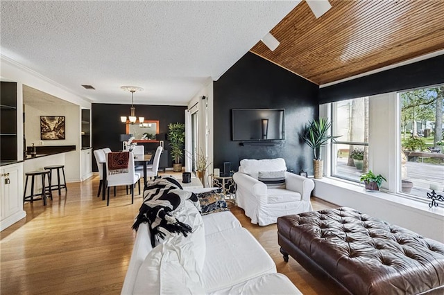 living area with visible vents, lofted ceiling, a textured ceiling, and light wood finished floors