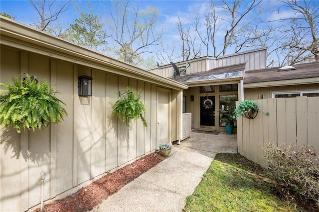 entrance to property featuring board and batten siding and fence