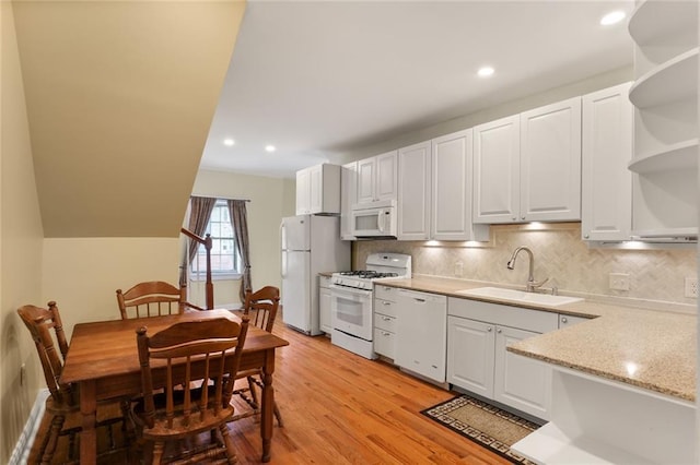 kitchen with white appliances, light wood finished floors, open shelves, a sink, and tasteful backsplash