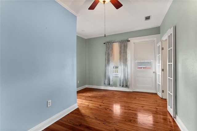 unfurnished room featuring visible vents, ornamental molding, wood finished floors, baseboards, and ceiling fan