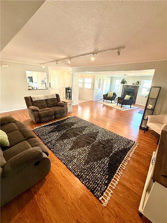 living room featuring a fireplace, a textured ceiling, and wood finished floors