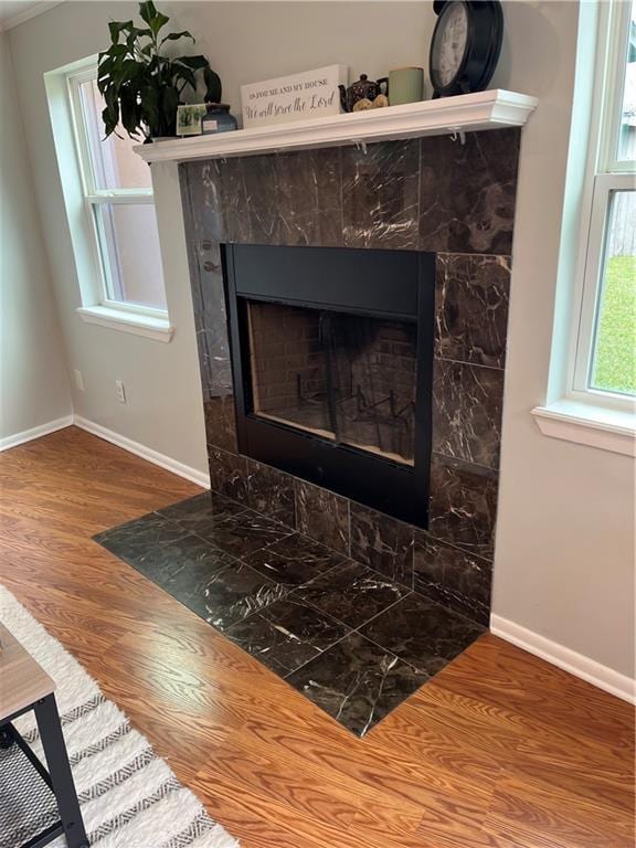 interior details featuring baseboards, wood finished floors, and a tiled fireplace