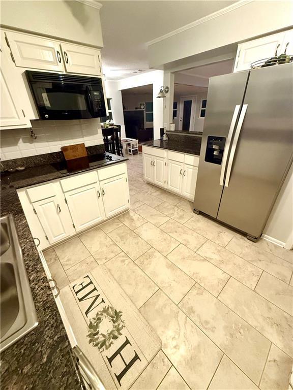 kitchen with dark countertops, white cabinets, stainless steel refrigerator with ice dispenser, and black microwave