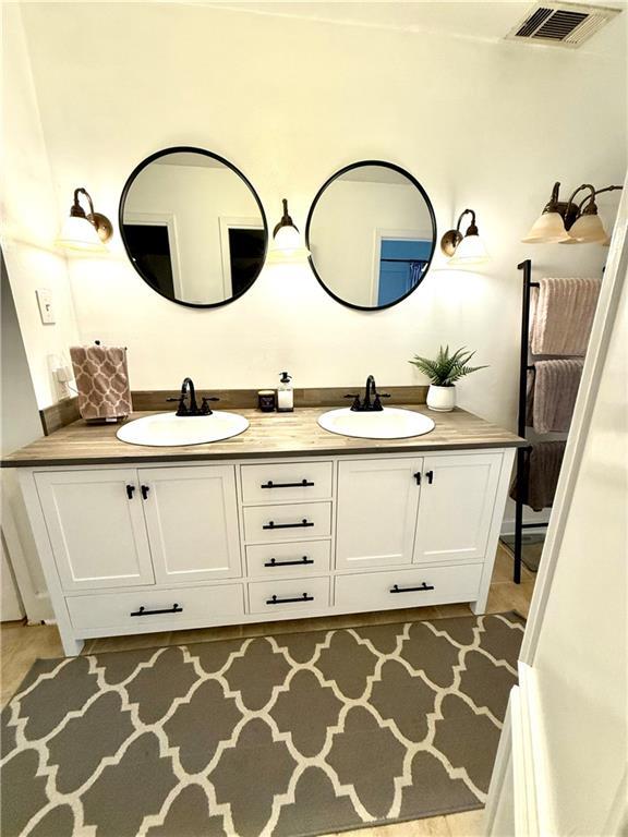 bathroom featuring double vanity, visible vents, and a sink