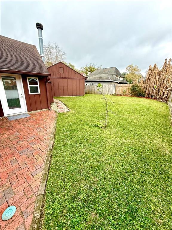 view of yard with a patio, a fenced backyard, and an outbuilding