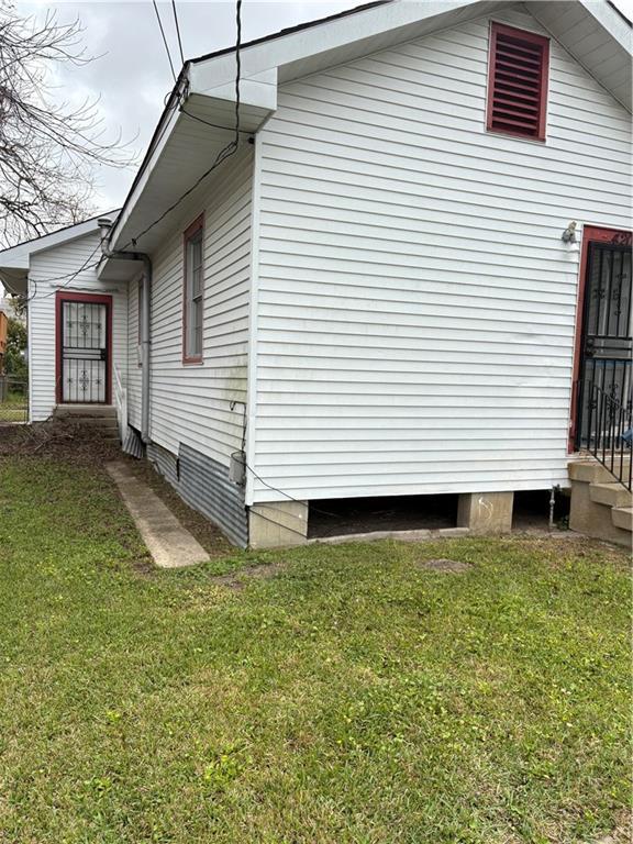 view of property exterior with entry steps and a lawn