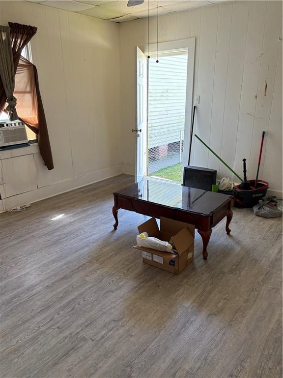 interior space with cooling unit, baseboards, and wood finished floors