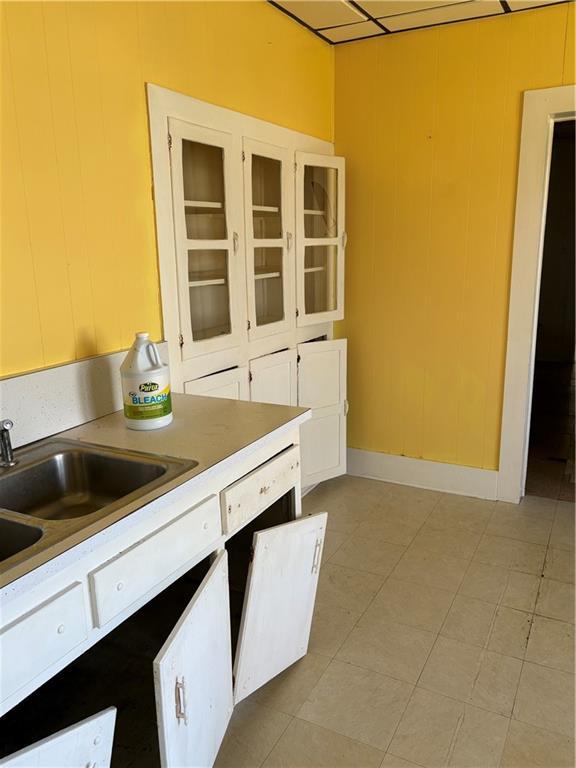 kitchen featuring light countertops, glass insert cabinets, and a sink