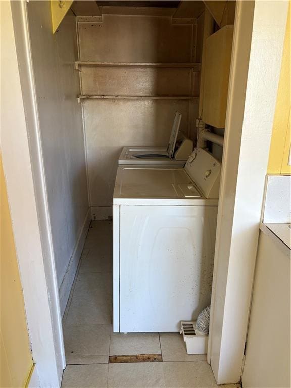 clothes washing area with light tile patterned floors, laundry area, and washer and clothes dryer