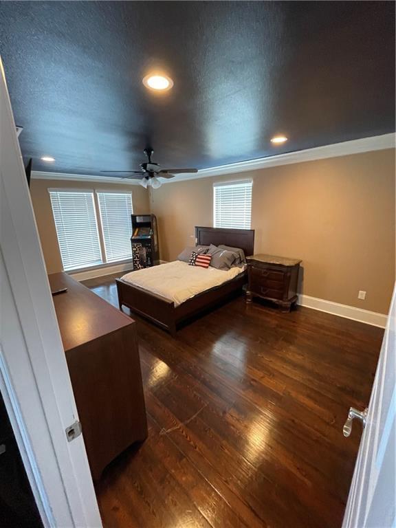 bedroom with ornamental molding, baseboards, dark wood-style flooring, and a textured ceiling