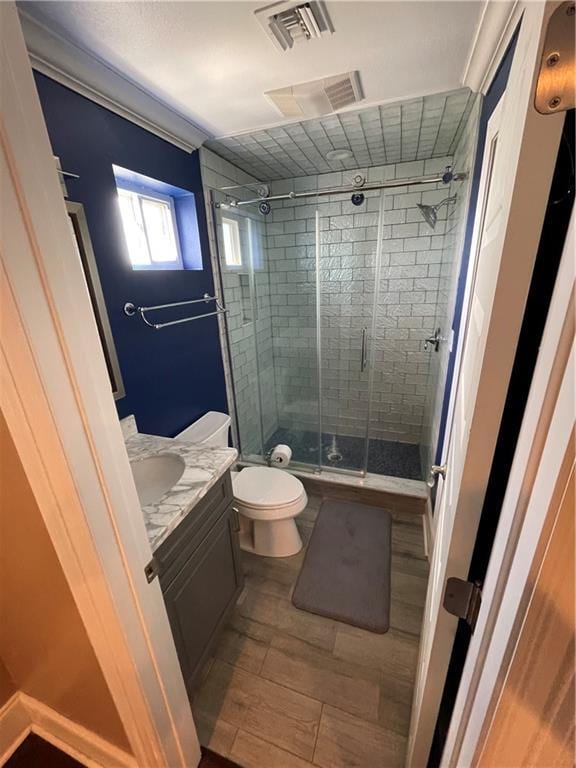 bathroom with visible vents, a stall shower, toilet, and vanity