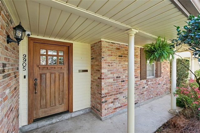 property entrance featuring brick siding and covered porch