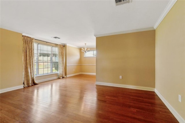 unfurnished room with visible vents, a healthy amount of sunlight, ornamental molding, an inviting chandelier, and wood finished floors