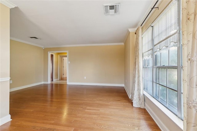 empty room with visible vents, baseboards, light wood-style flooring, and ornamental molding