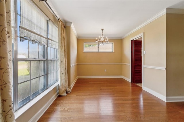 unfurnished dining area featuring an inviting chandelier, wood finished floors, baseboards, and ornamental molding