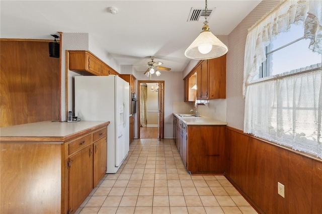 kitchen featuring brown cabinetry, visible vents, white fridge with ice dispenser, and ceiling fan