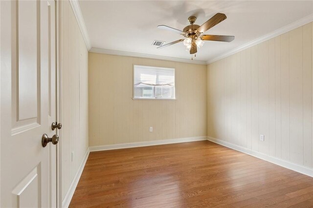 unfurnished room featuring ceiling fan, wood finished floors, visible vents, and ornamental molding