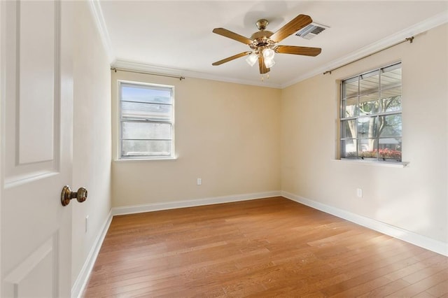 spare room with light wood-type flooring, visible vents, baseboards, and ornamental molding