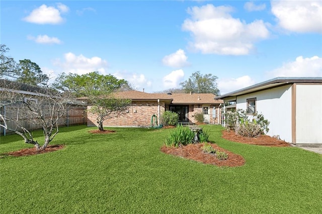 exterior space with a lawn, brick siding, and fence