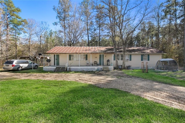 ranch-style home with metal roof, driveway, covered porch, and a front yard