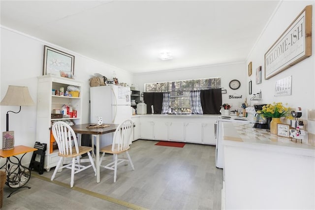 kitchen featuring white appliances, light countertops, light wood-style floors, white cabinetry, and crown molding