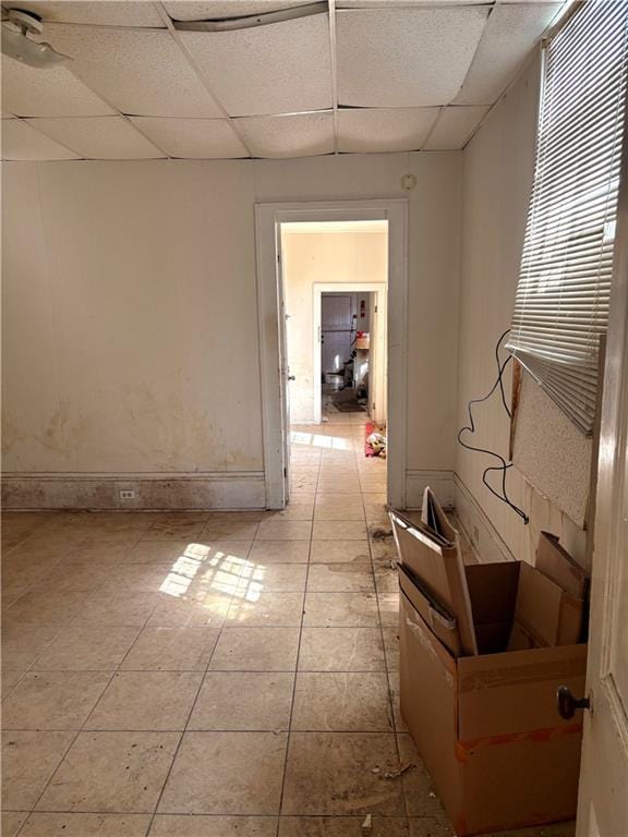 hallway with a drop ceiling and baseboards