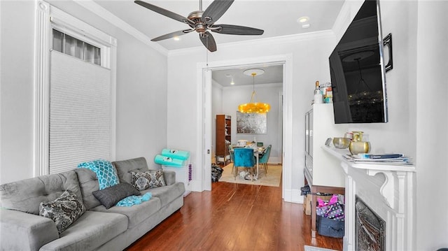 living area featuring a fireplace, ornamental molding, wood finished floors, and ceiling fan