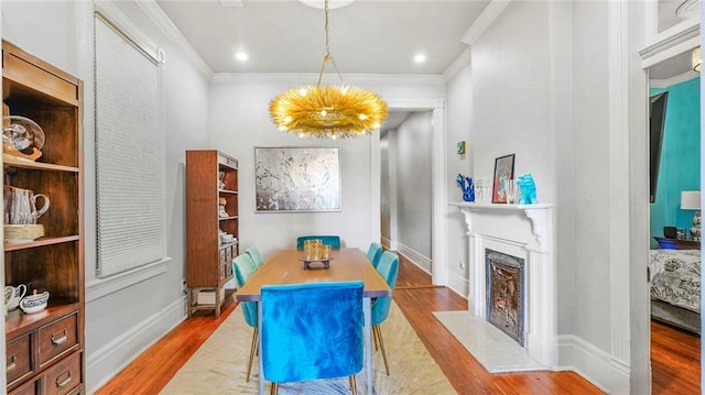 dining space with a fireplace with flush hearth, ornamental molding, and wood finished floors