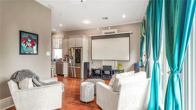 home theater room featuring recessed lighting, visible vents, wood finished floors, and ornamental molding