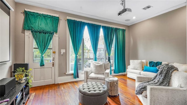 living area with visible vents, baseboards, hardwood / wood-style floors, and crown molding