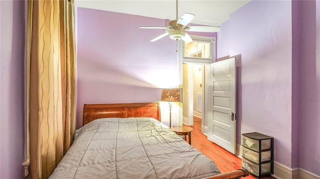 bedroom with a ceiling fan, wood finished floors, and baseboards