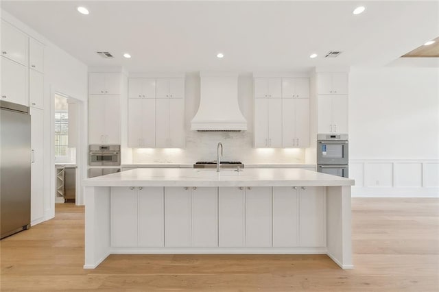 315 Sena Dr, Metairie, LA 70005 - kitchen featuring stainless steel appliances, light countertops, white cabinets, and premium range hood