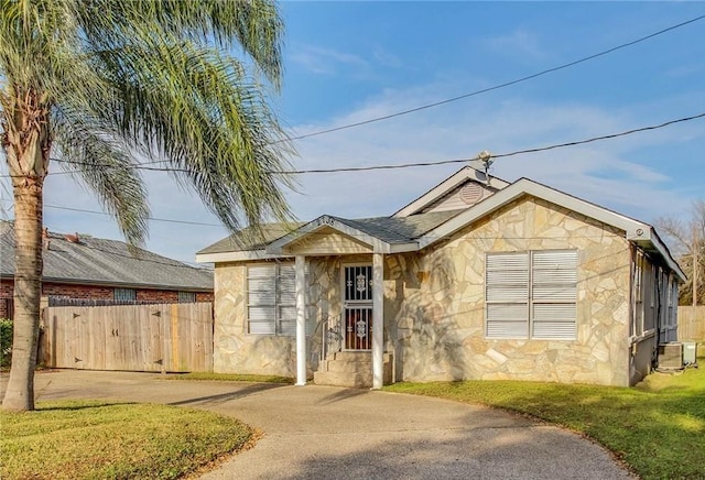 ranch-style home with stone siding, stucco siding, driveway, and fence