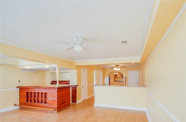 interior space featuring wood finished floors, a ceiling fan, baseboards, and ornamental molding