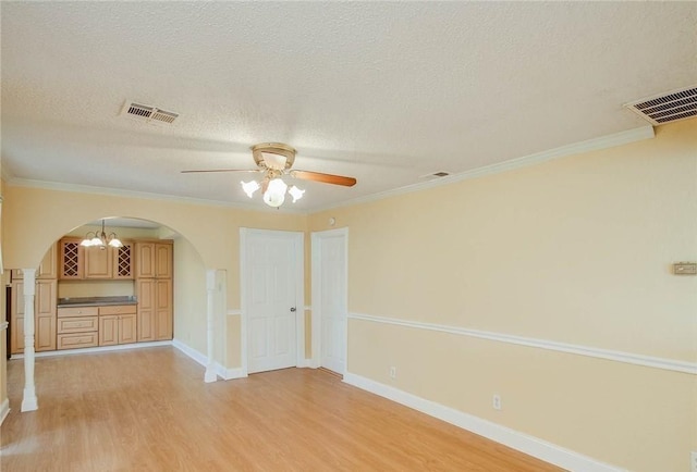 unfurnished room featuring visible vents, arched walkways, and light wood-style floors