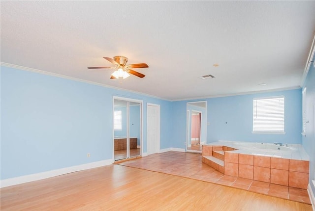 spare room with a ceiling fan, a healthy amount of sunlight, light wood finished floors, and ornamental molding