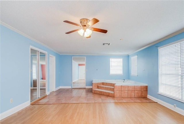 interior space with visible vents, light wood-style floors, a ceiling fan, and ornamental molding