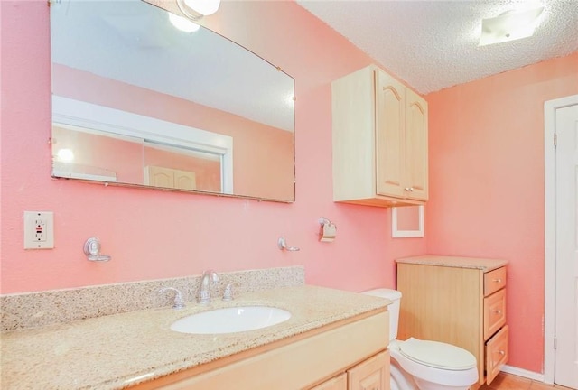 bathroom featuring a textured ceiling, vanity, and toilet