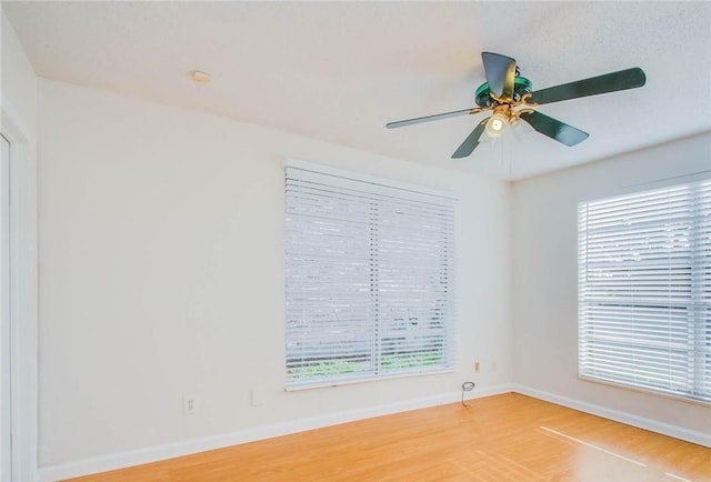 empty room with wood finished floors, baseboards, and ceiling fan