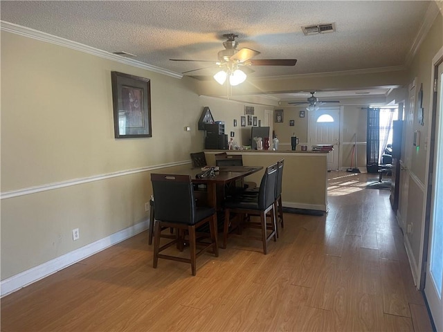 dining room with visible vents, ornamental molding, a textured ceiling, wood finished floors, and ceiling fan