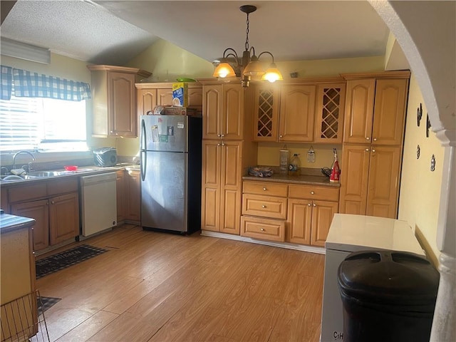 kitchen featuring white dishwasher, freestanding refrigerator, a sink, decorative light fixtures, and light wood-type flooring