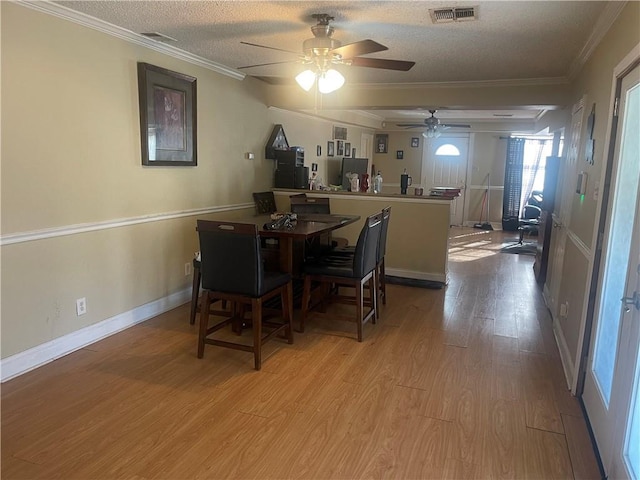 dining area with a ceiling fan, wood finished floors, visible vents, ornamental molding, and a textured ceiling