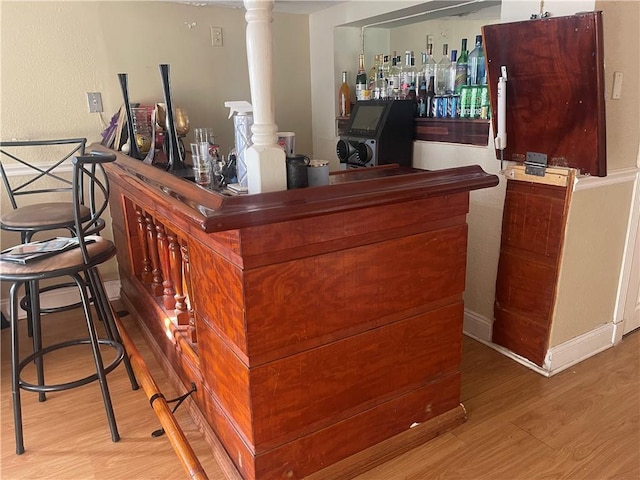 bar with light wood-style floors and ornate columns