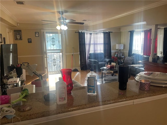 kitchen featuring crown molding, visible vents, stone counters, and ceiling fan