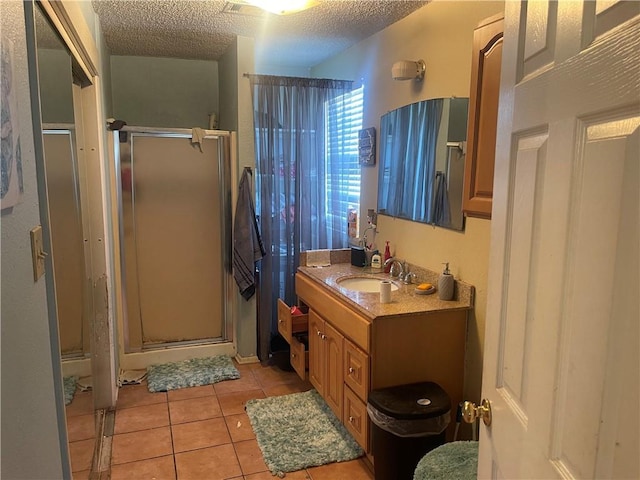 bathroom with tile patterned floors, vanity, a textured ceiling, and a shower stall