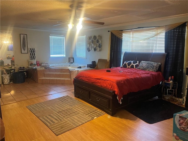 bedroom with a textured ceiling, crown molding, ceiling fan, and wood finished floors